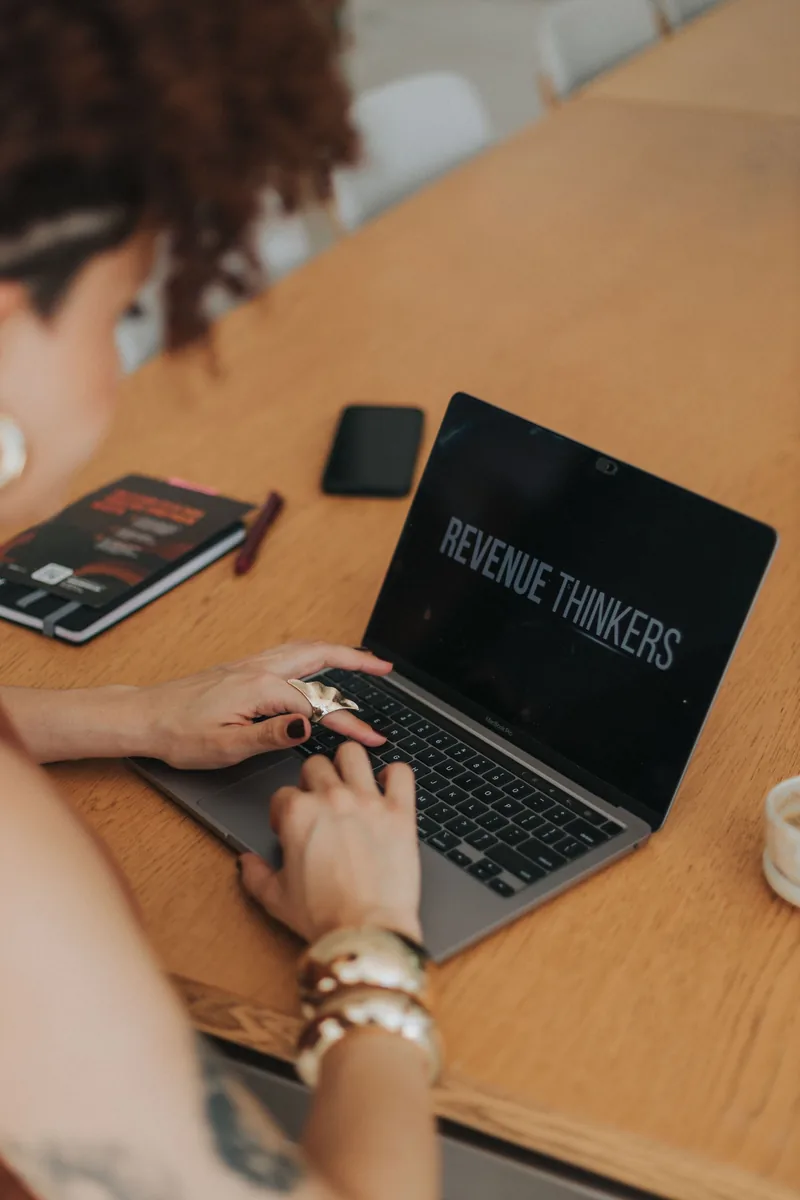 Amanda Alves trabalhando no MacBook com a marca Revenue Thinkers visível na tela